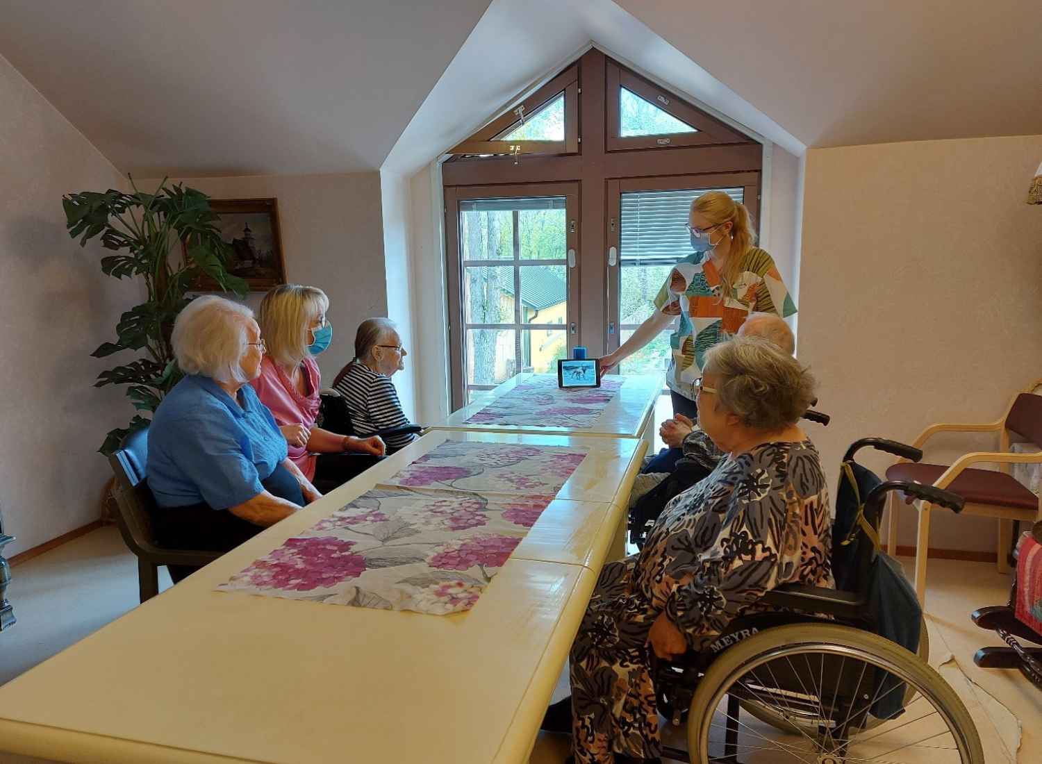 Kuva Palvelukoti Kokkilasta päivän yhteisestä hyvästä hetkestä. Ikääntyneitä ja hoitaja koolla Sävelsirkun ääreen.